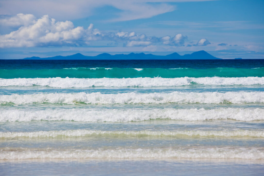 Waves crashing on beach with mountains in background