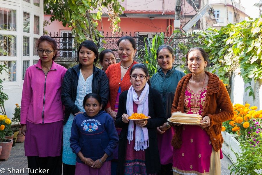 Eight Nepalese women standing in outdoor courtyard