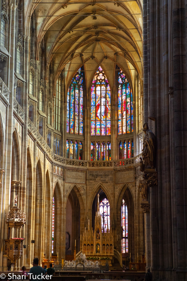 the inside of st. vitus cathedral in Prague showing the altar and stained glass windows